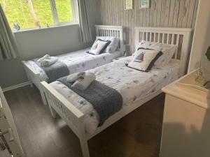 two white beds in a bedroom with a window at Frankie's Holiday Lodge in Gunnislake