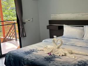 een slaapkamer met een bed met twee zwanen erop bij Baansuan Suksangob Farm Stay in Trang