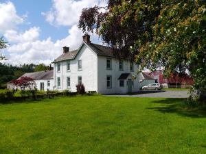 a white house with a car parked in front of it at Broomlands Farmhouse in Moffat