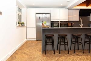 uma cozinha com armários brancos e bancos de bar em Bonneville House, Private Jacuzzi and Modern Interior em Londres