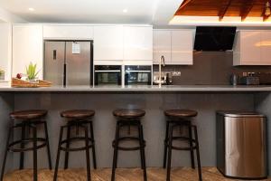 uma cozinha com um balcão com bancos de bar em Bonneville House, Private Jacuzzi and Modern Interior em Londres