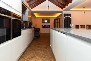 uma cozinha com armários brancos e uma bancada em Bonneville House, Private Jacuzzi and Modern Interior em Londres