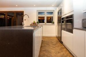 uma cozinha com armários brancos e um balcão preto em Bonneville House, Private Jacuzzi and Modern Interior em Londres