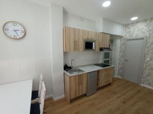 a kitchen with a sink and a clock on the wall at Xabucas in A Pobra do Caramiñal