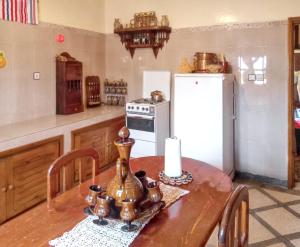 kuchnia z drewnianym stołem i białą lodówką w obiekcie 6 bedrooms villa with city view private pool and enclosed garden at Ait Ben Haddou w mieście Ajt Bin Haddu