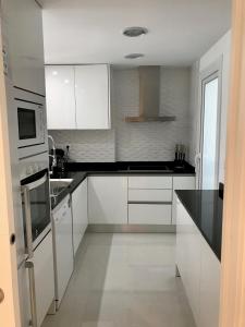 a kitchen with white cabinets and black counter tops at Sea Senses by Mar Holidays in Torrevieja