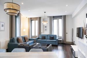a living room with blue couches and a tv at Slow Suites Gran Vía in Madrid