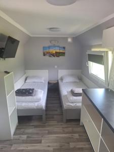 a small room with two beds and a tv at Chillout in Smołdzino