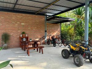 een atv geparkeerd onder een bakstenen gebouw met een tafel en banken bij Baansuan Suksangob Farm Stay in Trang