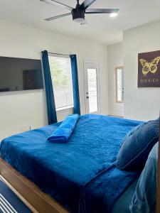 a bedroom with a blue bed with a ceiling fan at HTX Urban Oasis -Mins to Downtown, NRG, & Med Ctr! in Houston