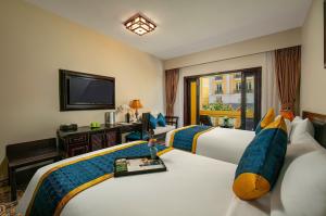 ein Hotelzimmer mit 2 Betten und einem TV in der Unterkunft Hanoi Golden Moon Hotel in Hanoi
