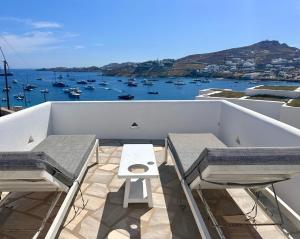 a balcony with two chairs and a table and a view of a harbor at Revel Mykonos 3 in Ornos +9 photos