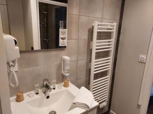 La salle de bains est pourvue d'un lavabo et d'un miroir. dans l'établissement Hotel Eisenhower (ex King Hôtel), à Port-en-Bessin-Huppain