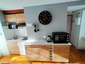 a kitchen with a microwave and a clock on the wall at Le 6 Magnifique Lafayette in Bagnères-de-Bigorre
