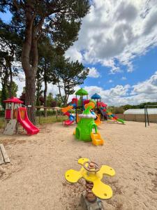 a playground with colorful play equipment in the sand at Camping Le Panoramic in Binic