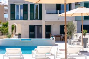 a pool with chairs and an umbrella next to a building at Villa La Familia in Sumartin +87 photos