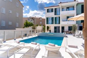 a swimming pool with chairs and a building at Villa La Familia in Sumartin
