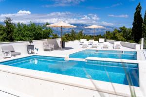 a swimming pool with chairs and umbrellas on a building at Villa La Familia in Sumartin