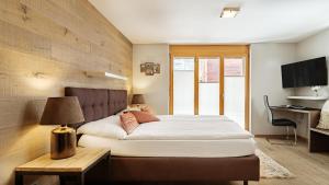 a bedroom with a bed and a table and a desk at Casa Della Luce Apartments in Zermatt