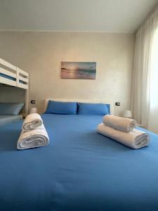 a bedroom with a blue bed with towels on it at Appartamento Villa Asio in Lignano Sabbiadoro