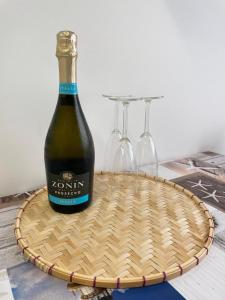a bottle of wine and two wine glasses on a basket at Appartamento Villa Asio in Lignano Sabbiadoro