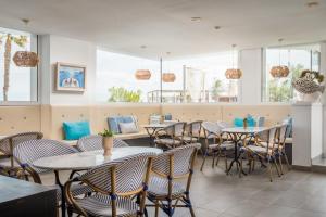 un restaurante con mesas, sillas y ventanas en ALEGRIA Mar Mediterrania - Adults Only 4*Sup en Santa Susanna