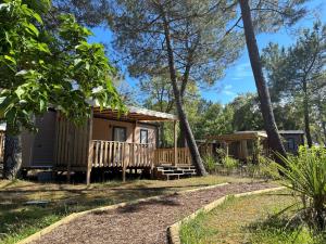 a cabin in the woods with a porch and trees at Camping Nature L'Airial in Soustons