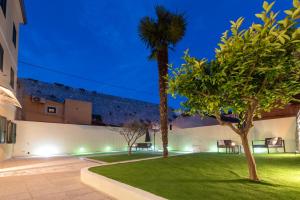een binnenplaats met gazon en palmbomen 's nachts bij Teuta Garden Luxury Room in Split