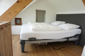 Una cama con sábanas blancas y almohadas. en Kustverhuur, 't Uusje Nieuwvliet, en Nieuwvliet