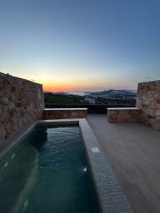 a swimming pool with a sunset in the background at Aroma Cavas in Pirgos