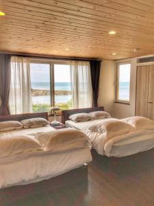 three beds in a room with windows and the ocean at Populus Sunset "You-hi"-Atsuta - Vacation STAY 05432v in Ishikari