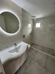La salle de bains blanche est pourvue d'un lavabo et d'un miroir. dans l'établissement Aroma Cavas, à Pyrgos
