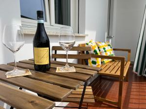 a bottle of wine sitting on a wooden table with two glasses at Casa Margherita (Alba) in Alba