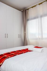 a bedroom with a bed with white cabinets and a window at Comfort & Style 1Bed Apartment, Luxore, Syokimau in Nairobi