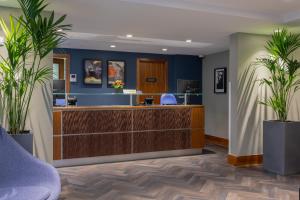 an office lobby with a reception desk and two potted plants at The Scholar in Edinburgh