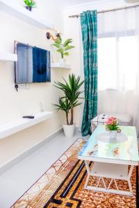 a living room with a table and a tv at Comfort & Style 1Bed Apartment, Luxore, Syokimau in Nairobi