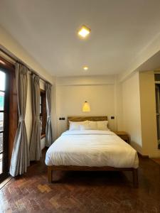 ein Schlafzimmer mit einem großen weißen Bett und einem Fenster in der Unterkunft Karuna Hotel Patan Kathmandu in Pātan