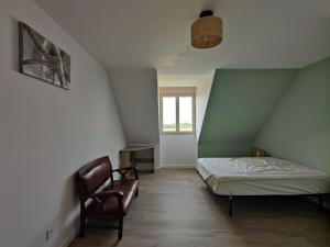 een kleine slaapkamer met een bed en een stoel bij Camping la Haie Penée **** in Saint-Quentin-en-Tourmont