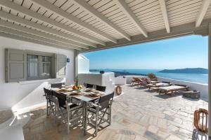 un patio con mesa, sillas y el océano en 180° Caldera by Stylish Stays, en Firostefani