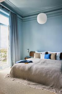 Dormitorio azul con cama y ventana grande en stilwerk Strandhotel Blankenese en Hamburgo