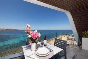 una mesa con una botella de vino y flores en el balcón en Ivory Suite Seafront With Views!- Fl 14 By Homely, en St Paul's Bay