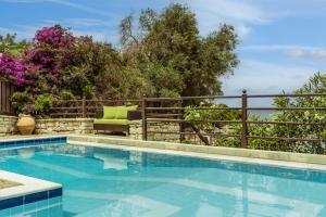 ein Pool neben einem Zaun mit einer Couch in der Unterkunft Anassa Mare Villas & Residences in Gaios