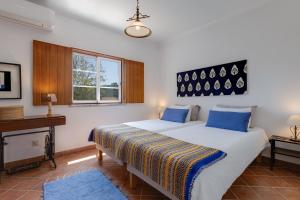 a bedroom with a bed with blue pillows and a piano at Sesmarias MEL Casas Gémeas para Famílias Grandes in Cercal +19 photos