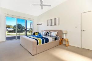 a bedroom with a bed and a large window at Riversea Goolwa Beach House in Goolwa