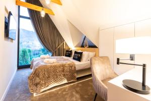 a bedroom with a bed and a chair and a window at Skyline Villa with jacuzzi and sauna in Kościelisko