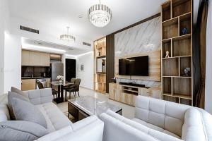 uma sala de estar com dois sofás brancos e uma televisão em Stayis -Spacious & Luxury 1 Bedroom room Apartment em Dubai