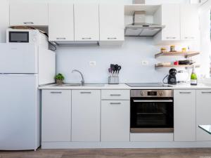uma cozinha branca com armários brancos e um forno em El Drago Apartment Fiber ,A/C,Near Ocean em Costa Del Silencio