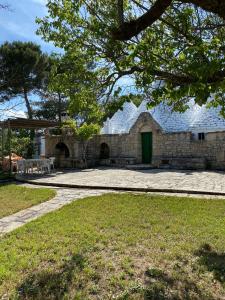ein Steingebäude mit einer grünen Tür im Hof in der Unterkunft Trullo Oasi di Pace in Ceglie Messapica