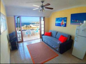 een woonkamer met een bank en een televisie bij Ático con impresionantes vistas al mar in Adeje