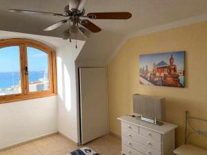 een kamer met een plafondventilator, een dressoir en een raam bij Ático con impresionantes vistas al mar in Adeje